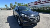 Black Hyundai SUV in a dealership lot, with an E-Z Loan Auto storefront in the background under a clear blue sky.