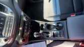 Interior of a car showing the center console with cup holders, gear shifter, and climate/radio controls, plus a paper on the floor near the seat.