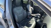 Front interior of a Jeep with black leather seats, two front seats visible, gear shifter and center console in view, open passenger door showing outside parking lot.