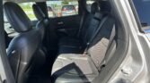 Rear passenger area of a black SUV with black leather seats, three headrests, and visible seat belts; parking lot seen through the side windows.