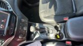 Center console in a car showing the gear shifter, cup holder, and control buttons beside the driver seat area