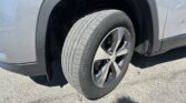 Close-up of a vehicle's front wheel and tire inside a gray fender, showing a Goodyear tire on an alloy rim.
