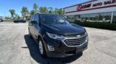 Black Chevrolet SUV parked in a car lot in front of EZ LOAN AUTO SALES under a clear blue sky with trees in the background.