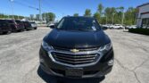 Front view of a black Chevrolet SUV in a sunny dealership parking lot with other cars in the background.