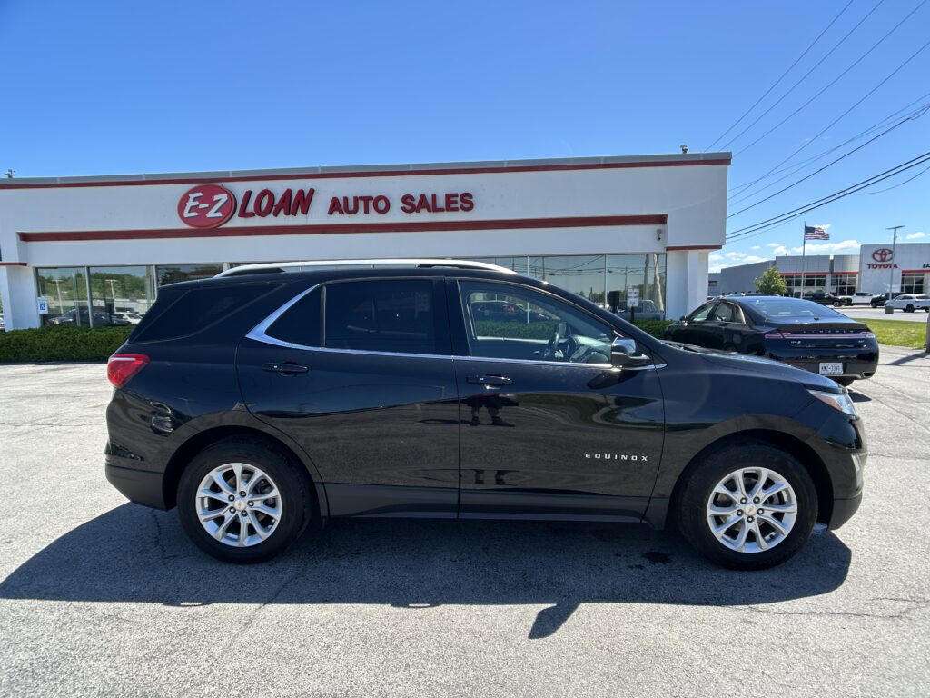 Black Chevrolet Equinox parked in front of an E-Z Loan Auto Sales storefront on a sunny day