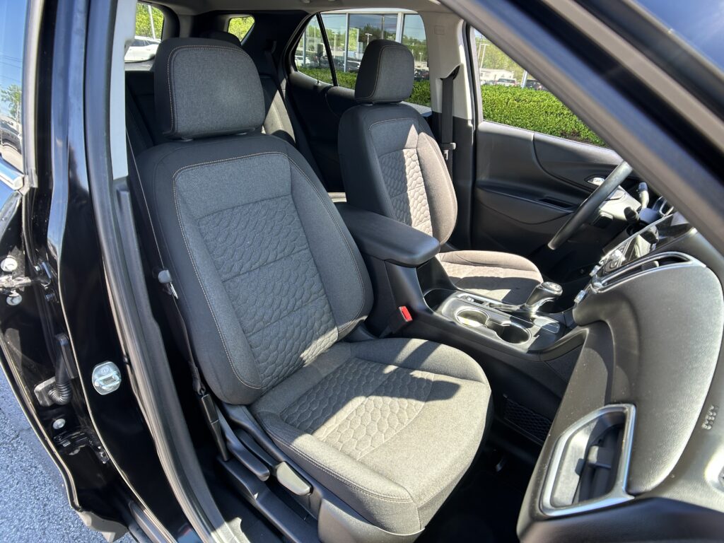 Interior of a car showing driver and front passenger seats with black fabric upholstery and stitching separate from other interior features.