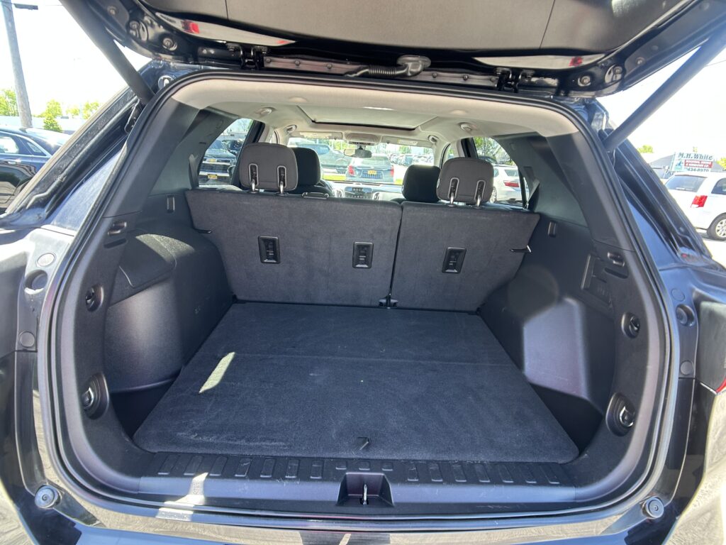 Open SUV tailgate revealing a large, empty cargo area with the rear seats in upright position, parked in a lot.