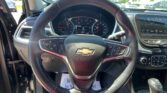 Steering wheel with Chevrolet emblem, dashboard gauges, and an in-dash infotainment screen in a bright car interior