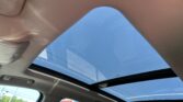 Interior of a car showing an open sunroof with blue sky visible through the skylight.