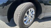Close-up of a black SUV's front wheel and fender, showing a treaded tire with Chevrolet center cap.