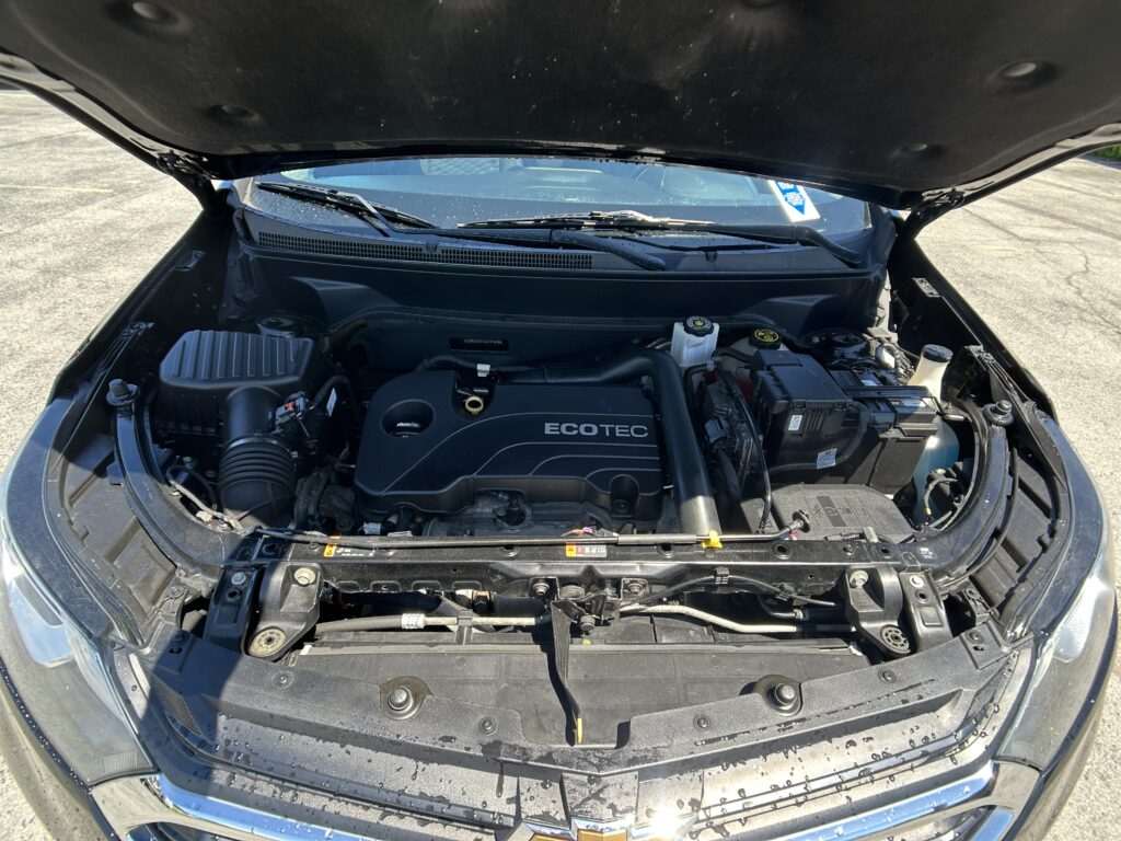 Open car hood exposing the engine bay, with an Ecotec engine cover and visible battery and fluid reservoirs