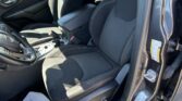 Interior of a dark car showing the driver and front passenger seats, center console, and papers on the floor near the door, parked in a lot.