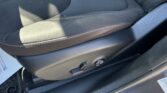 Driver's seat bottom cushion in black fabric with white contrast stitching and a side adjustment lever visible under the seat edge.