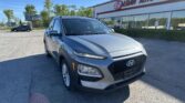 Silver Hyundai SUV in a parking lot in front of the EZ Auto Sales building with a clear blue sky above.