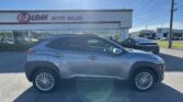 Front view of a silver SUV parked in a dealership lot in front of the E-Z Loan Auto Sales building on a sunny day.