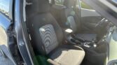 Interior of a car showing front passenger and driver seats, open driver door, daytime light glare on seats and dashboard.