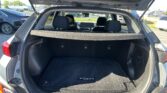 Open rear hatch reveals spacious cargo area of a Kia Kona with folded/fold-down third row seats and black carpeting