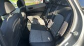 Rear interior of a compact SUV showing the back seat with three upholstery seats, headrests, and seat belts; sunlit window view outside.