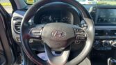 Driver's view of steering wheel with Hyundai logo, dashboard gauges, and infotainment screen visible to the right.