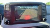 Rearview camera display on car dash showing parking guidelines and a parking lot behind the vehicle. Text on screen reads: 'Check surroundings for your safety.'