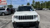 Front view of a white Jeep SUV in a car dealership lot, with a blue sky and EZ LOAN Auto Sales sign nearby.