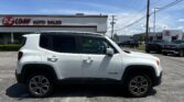 White SUV (Jeep Renegade) parked in a car lot in front of an E-Z Loan Auto Sales building under a blue sky with power lines overhead.