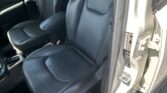 Interior of a car showing black leather front seats with headrests and an open door; outside parking lot visible.