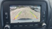 Car infotainment screen showing rearview camera with parking guide lines as you back up in a parking lot.