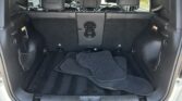 Open SUV trunk showing black floor mats piled on the cargo floor, with rear seats visible in the background/three-row seating setup in view.