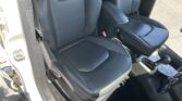 Inside a car showing black leather front seats with white stitching, and the center console with gear shifter visible.