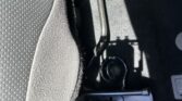 Close-up of the car interior showing a metal seat adjustment lever near the floor by the driver's seat with textured upholstery nearby.