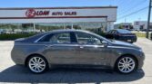 Side view of a gray sedan parked in front of an E-Z LOAN Auto Sales storefront on a sunny day.