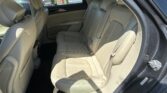 Beige leather rear seats with headrests in a car interior, showing seat belts and door panel.