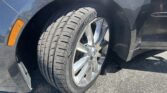 Close-up of a car wheel and tire inside the wheel well, with an orange side marker on the fender visible beside the tire.