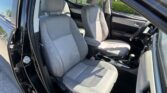 Front passenger and driver seats in a car, gray fabric upholstery, with the driver's door open showing the interior layout and center console.