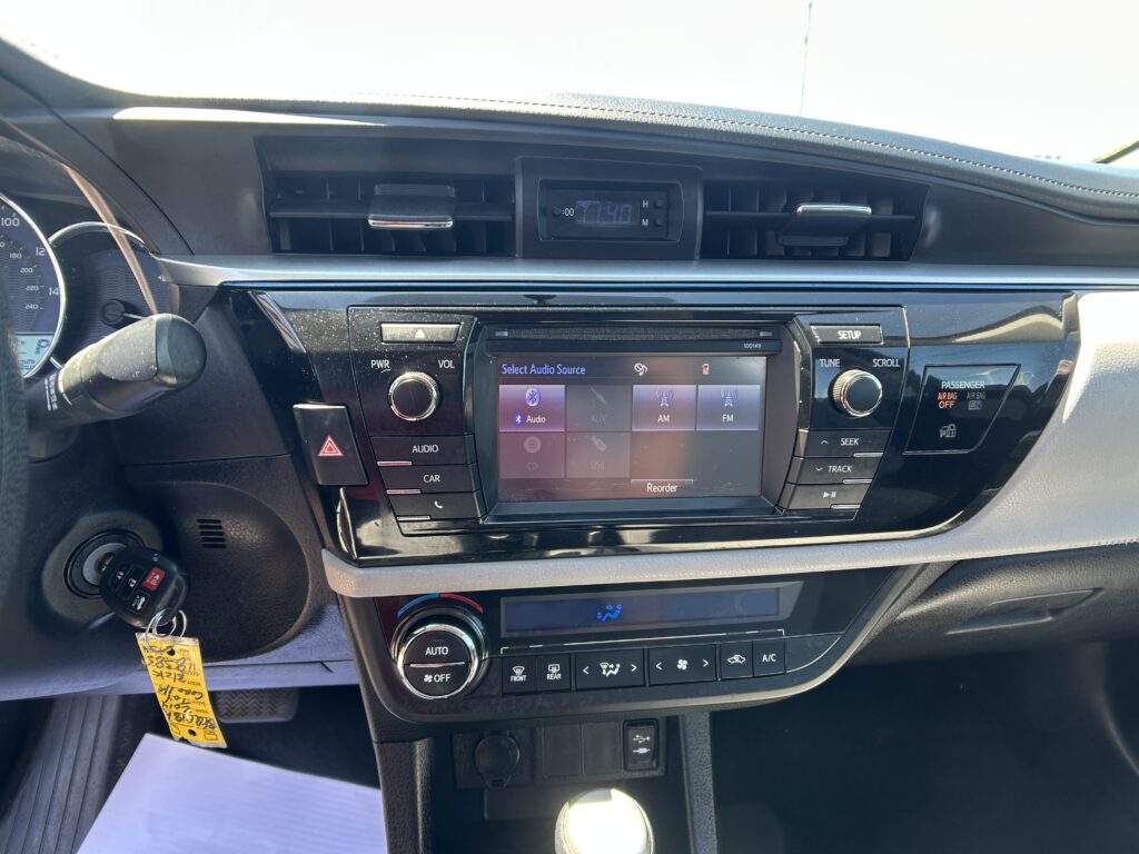 Center-dash view: dual air vents, small digital clock between vents, and a touchscreen infotainment system below.
