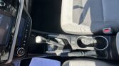 Interior of a car showing the center console with gear shifter, cup holders, and a gray passenger seat nearby.