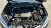 Open car hood showing the engine bay with a black Dual VVT-i engine cover, coolant reservoir and various hoses visible.