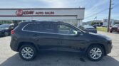 Front view of a dark blue Jeep Cherokee parked in a car lot in front of EZ LOAN Auto Sales building.