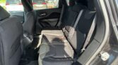 Back seat area of a black SUV showing three seats with three seat belts and headrests, interior door panel, and view of cars outside through the windows.