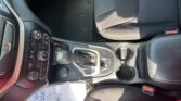 View of a vehicle's center console and front passenger seat area, showing the gear shifter, climate controls, cup holders, and a Jeep-branded floor mat beneath the pedals.