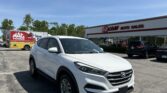 White Hyundai SUV parked in front of E-Z Loan Auto Sales on a sunny day in a dealership lot.