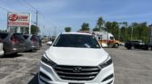 Front view of a white Hyundai SUV parked in a dealership lot, with an E-Z LOAN Auto Sales sign visible in the background on the left.