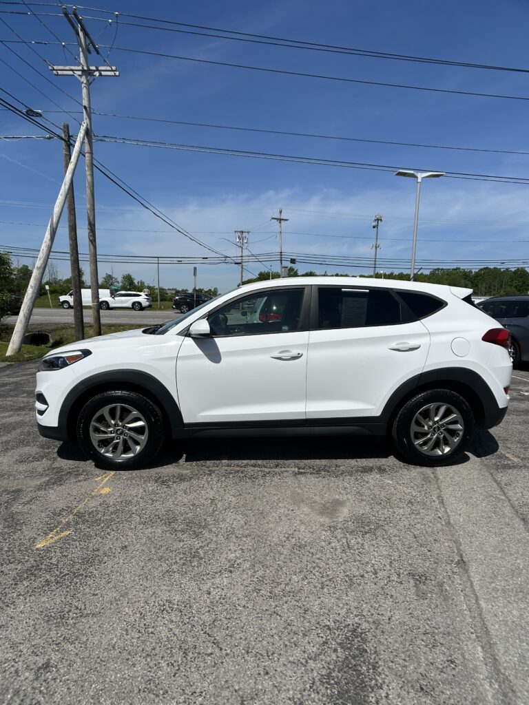 White SUV parked in a lot with power lines overhead and a blue sky behind.
