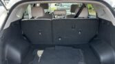 Open trunk of a white SUV showing folded third-row seats, black cargo liner, and floor mat marked 'TUCSON'