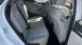 Open rear passenger door shows light-gray fabric back seats in a white SUV interior