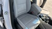 Light gray car interior showing the front passenger and driver seats, center console, and open door.