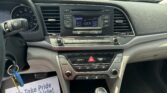 Dashboard view of a car with the radio on the center console showing 106.5 FM and a flyer on the floor reading ‘We Take Pride In Your Vehicle’.]},{