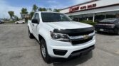 White pickup truck in the foreground at EZ Auto Sales dealership on a sunny day with a blue sky above.