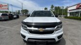 Front view of a white Chevrolet pickup parked in a car dealership lot, with the EZ Auto Sales building in the background and other vehicles nearby.